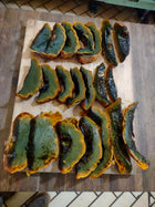 Roasted Guatemalan Green Ayote slices on a wooden board, green rind with orange flesh
